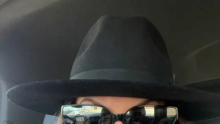 Bethenny Frankel, wearing a black hat, black sunglasses, and a cream fluffy coat, looking into the camera.