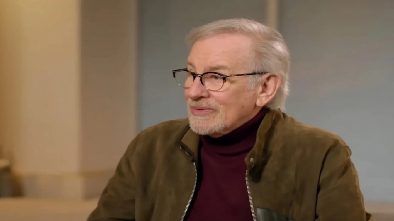 Steven Spielberg in a brown jacket and glasses.