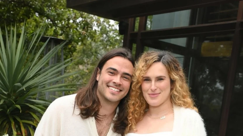 Rumer Willis, wearing a white dress, and Derek Richard Thomas, wearing a white shirt, pose together at her baby shower.