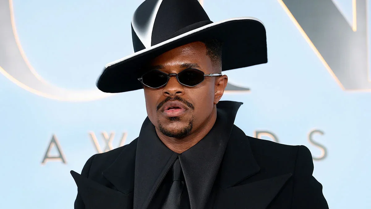 Jeremy Pope showcases a dramatic black-and-white Robert Wun ensemble with sculptural hat at the Tony Awards.