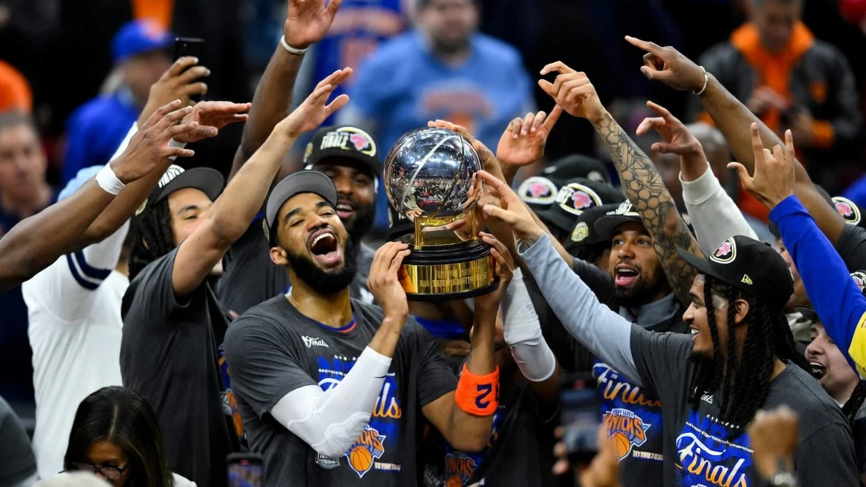 New York Knicks center Karl-Anthony Towns lifts the 2026 Eastern Conference trophy with teammates.