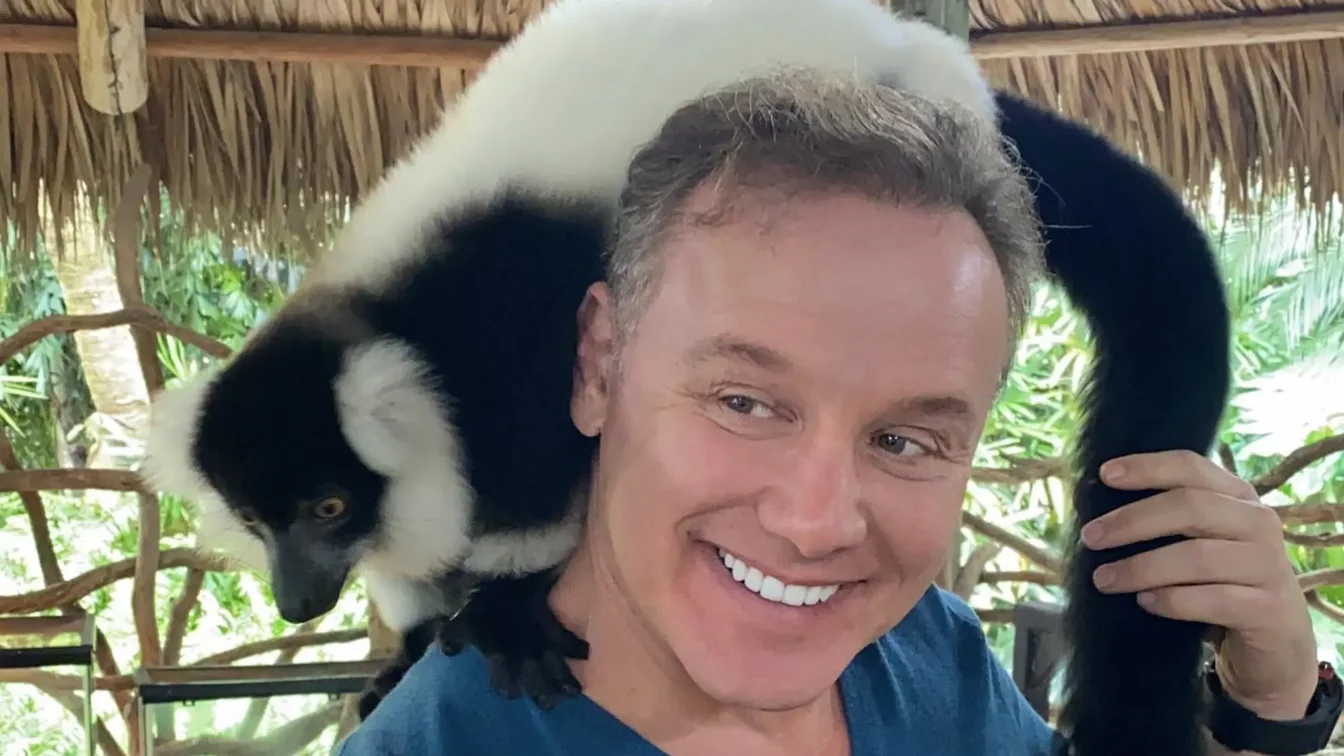 Lenny Hochstein with a black and white ruffed lemur on his shoulders.