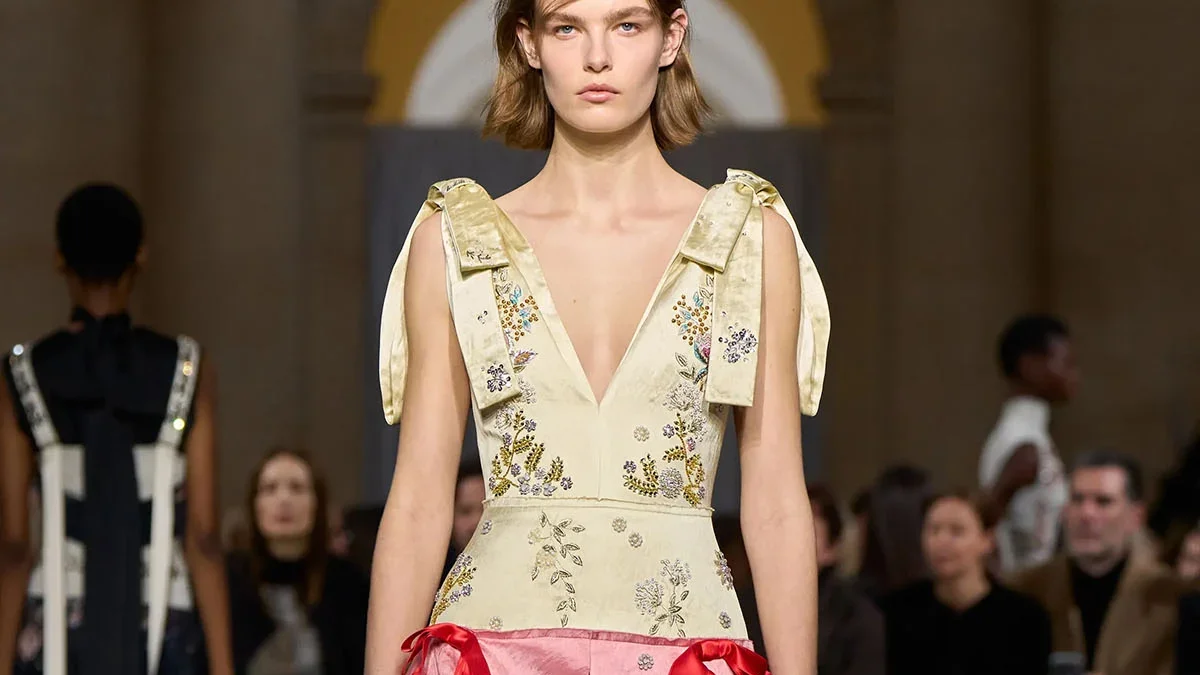 Model walks the Erdem runway wearing the ivory and pink embroidered dress from the Fall 2026 collection.